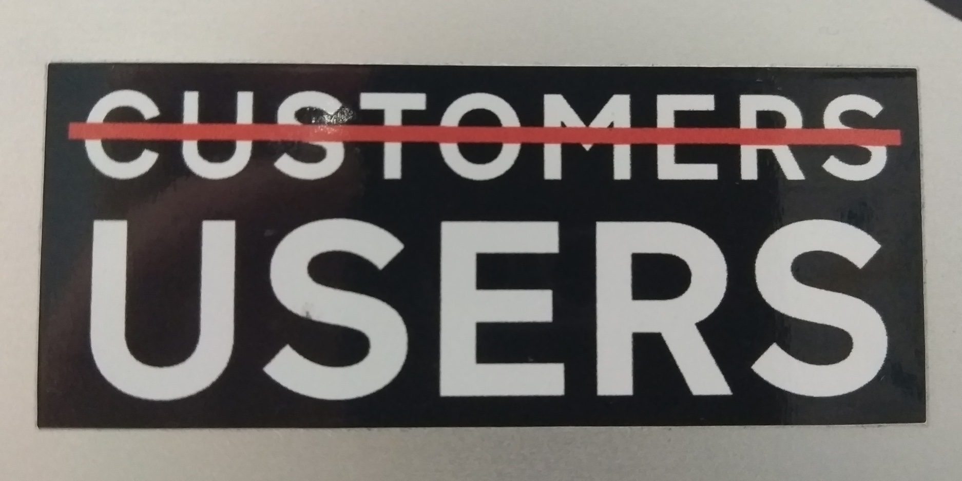 A sticker that used to circulate in design circles in UK Government department, showing the word 'customers' striked out and a big 'users' instead.